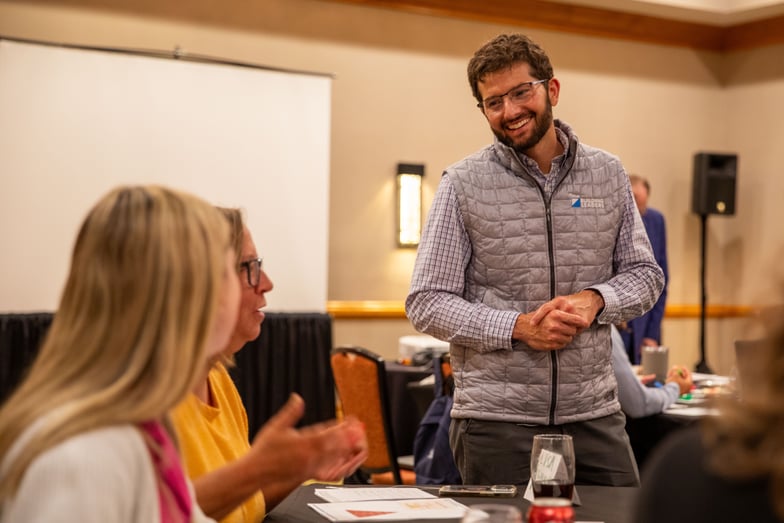 man smiling next to table of people