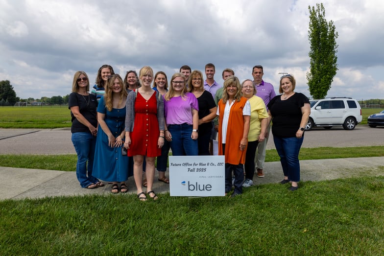 The Columbus, Indiana office team poses for a photo in front of a sign announcing the future office location