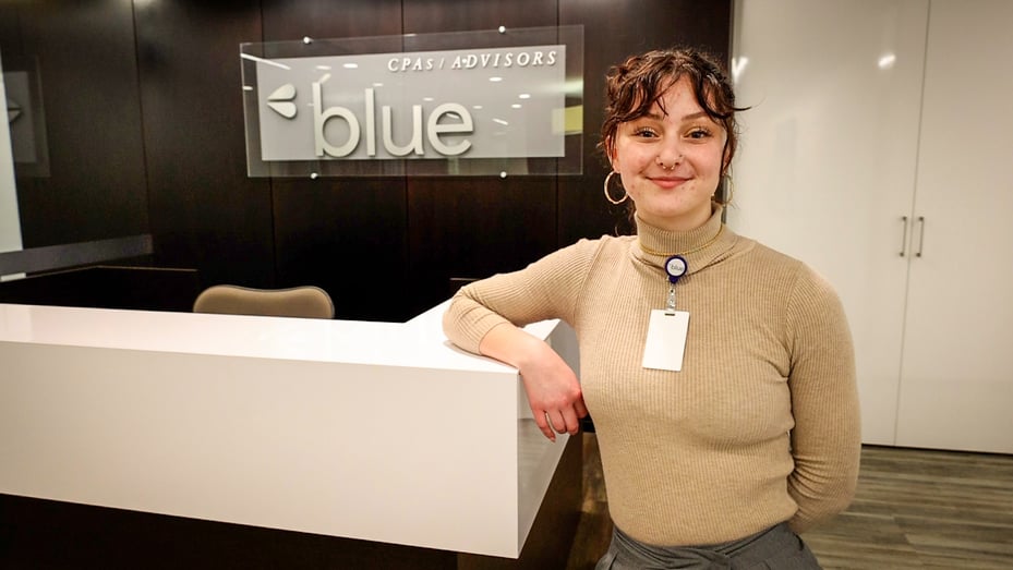 Intern Abigail Watson standing in front of 'Blue' sign in Indianapolis office