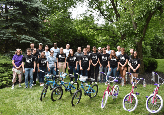 group photo of people standing behind bicycles