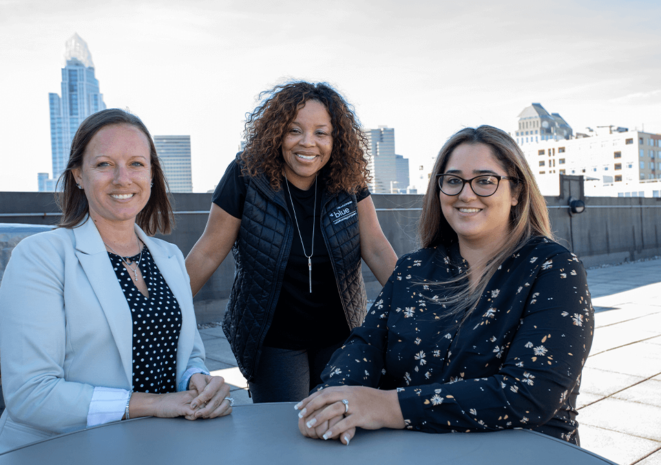 three business women smiling on patio rooftop 