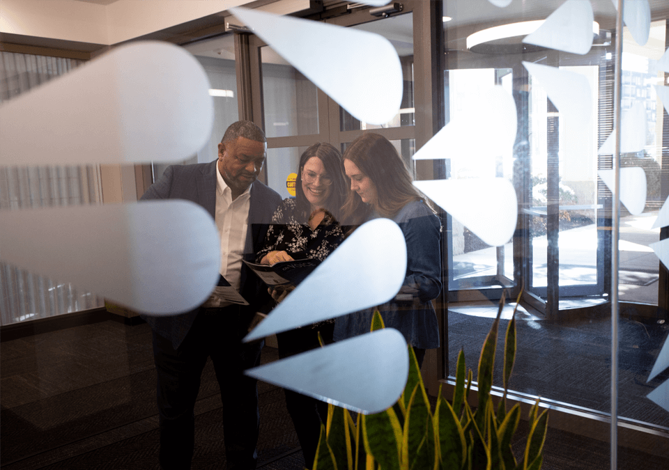 three employees looking at a magazine in office