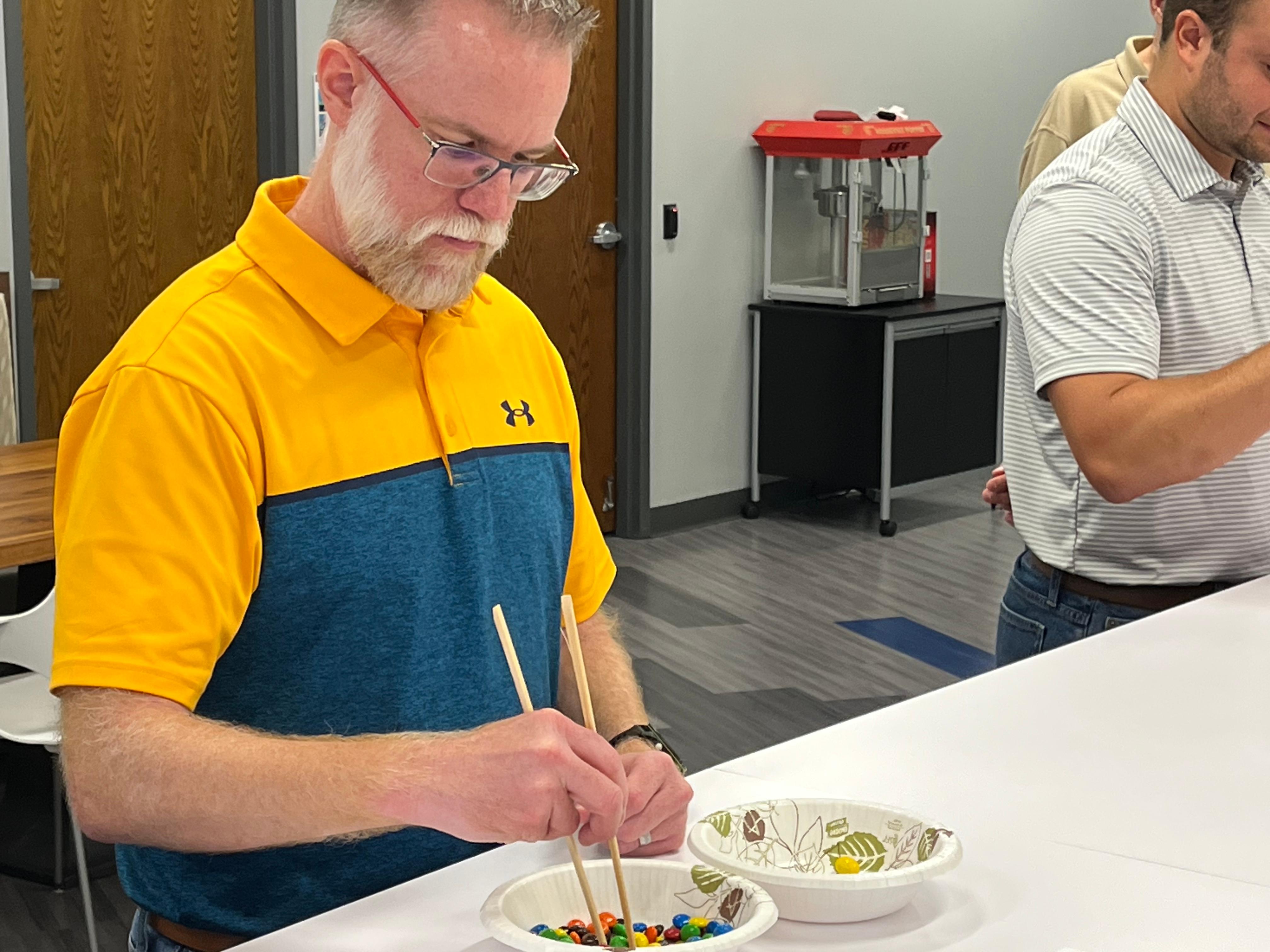 Columbus Ohio Director Scott Wilson attempts to pick up m&m's with chopsticks as part of the Office Olympic Games
