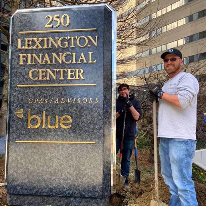 Employees pose beside the Lexington Financial Center sign during a clean-up community service day