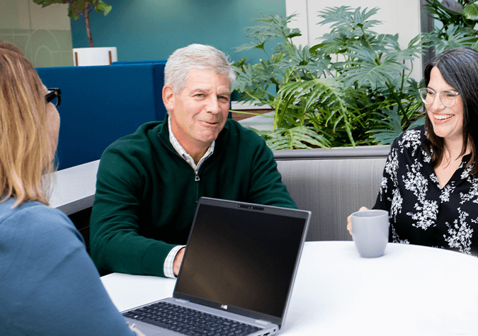 woman with laptop talking to couple