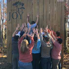 Building Leaders group trying to climb wall at Camp Joy ropes course