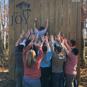 2023 Building Leaders Team lifting teammate over wall at Camp Joy event | Building Leaders: An Award-Winning Leadership Program at Blue
