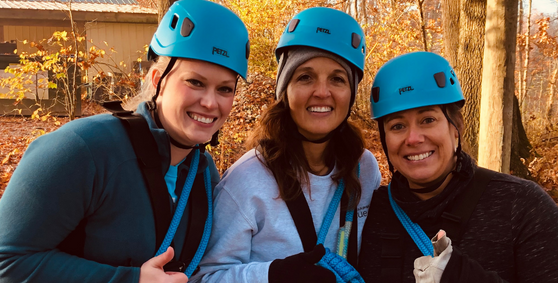 Three women smiling in helmets at ropes course for Building Leaders