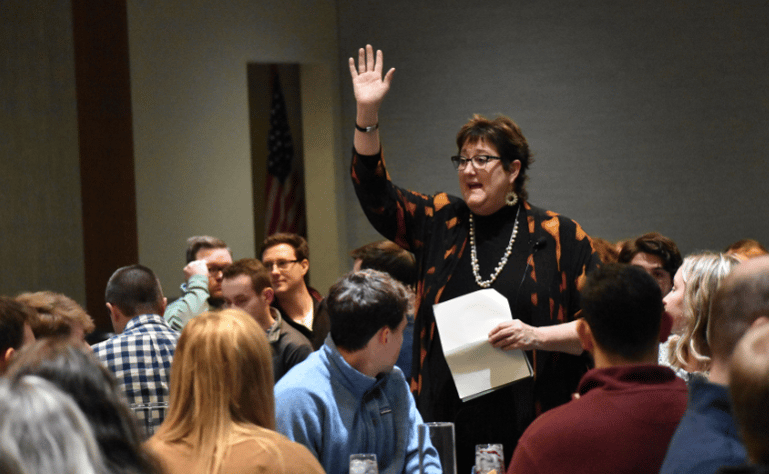 Jan Green calling attention to large dining room at Etiquette Dinner