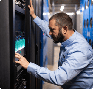 Man in button up shirt looking at computer servers