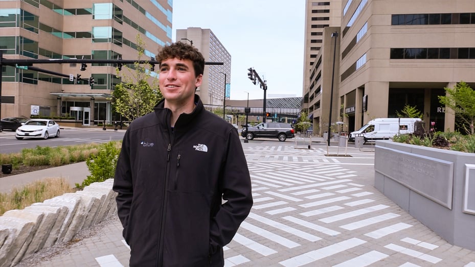 Blue intern Matthew Messer wears a Blue branded jacket and walks down the street in Lexington, Kentucky in front of the Blue office