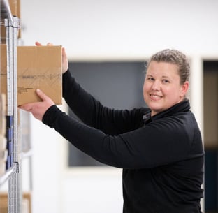 Female IT support specialist smiling and loading equipment onto storage rack