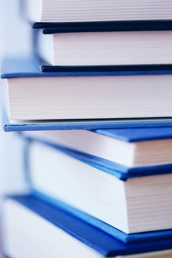 Close-up photo of blue textbooks stacked on top of each other | The Blue Foundation Launches 2024 Scholarship Application