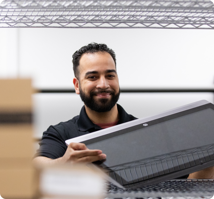 Smiling IT expert lifting laptop off of shelf